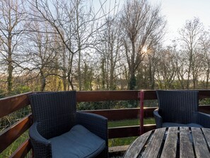 A wooden deck with wicker chairs and a table, overlooking a wooded area. - Vestingsplek by Interhome (Veere)
