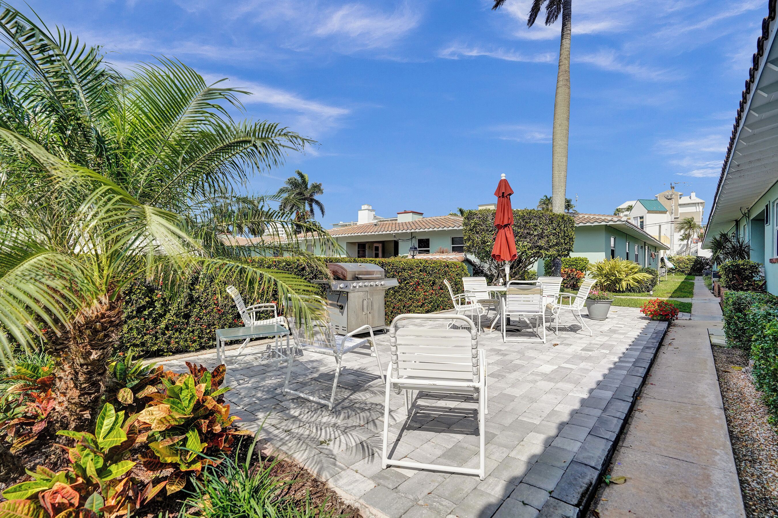 A patio area with outdoor furniture, a grill, and a pathway leading to a building.