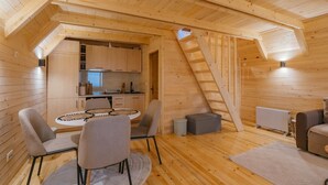 Une charmante cabane en bois dotée d’un coin repas, d’une cuisine et d’une chambre à coucher située en mezzanine.