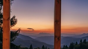 Une vue sur un paysage montagneux, avec un coucher de soleil visible à travers une structure en bois.