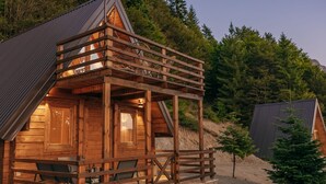 Une cabane en bois dotée d’un balcon, d’un porche et d’une petite terrasse.