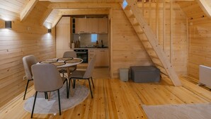 Un intérieur chaleureux en bois, comprenant un coin repas, une cuisine et un escalier.