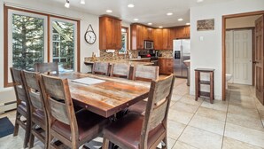 Una cocina amplia con armarios de madera, un refrigerador de acero inoxidable y un comedor con mesa y sillas de madera.