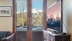 A living room with a large window, a television, and a framed picture on the wall. - Raven 7 minute walk to Main St/Downtown Breck. Hot tub! (Breckenridge)