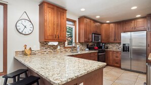 A kitchen with wooden cabinets, granite countertops, stainless steel appliances, and a clock on the wall. - Raven 7 minute walk to Main St/Downtown Breck. Hot tub! (Breckenridge)