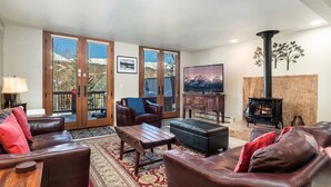 A spacious living room with leather sofas, a wooden coffee table, and a fireplace. - Raven 7 minute walk to Main St/Downtown Breck. Hot tub! (Breckenridge)