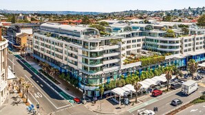 A modern multi-story hotel with curved balconies and rooftop gardens.