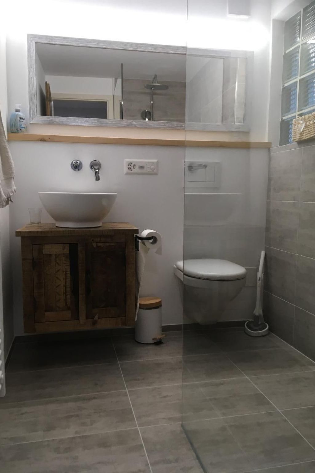 Kylpyhuoneessa on valkoinen pesuallas, wc ja suihku. Pesualtaan alla on puinen kaappi ja wc:n vieressä roskakori.