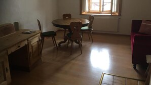 Un comedor con una mesa y sillas de madera, una ventana con cortinas y un radiador.