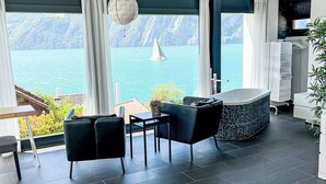 Ein modernes Zimmer mit Seeblick, einer Badewanne und einem Essbereich.