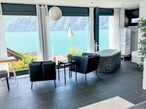 A modern room with a view of a lake, a bathtub, and a dining area. - Ferienvilla am See 3 by Interhome (Sisikon)