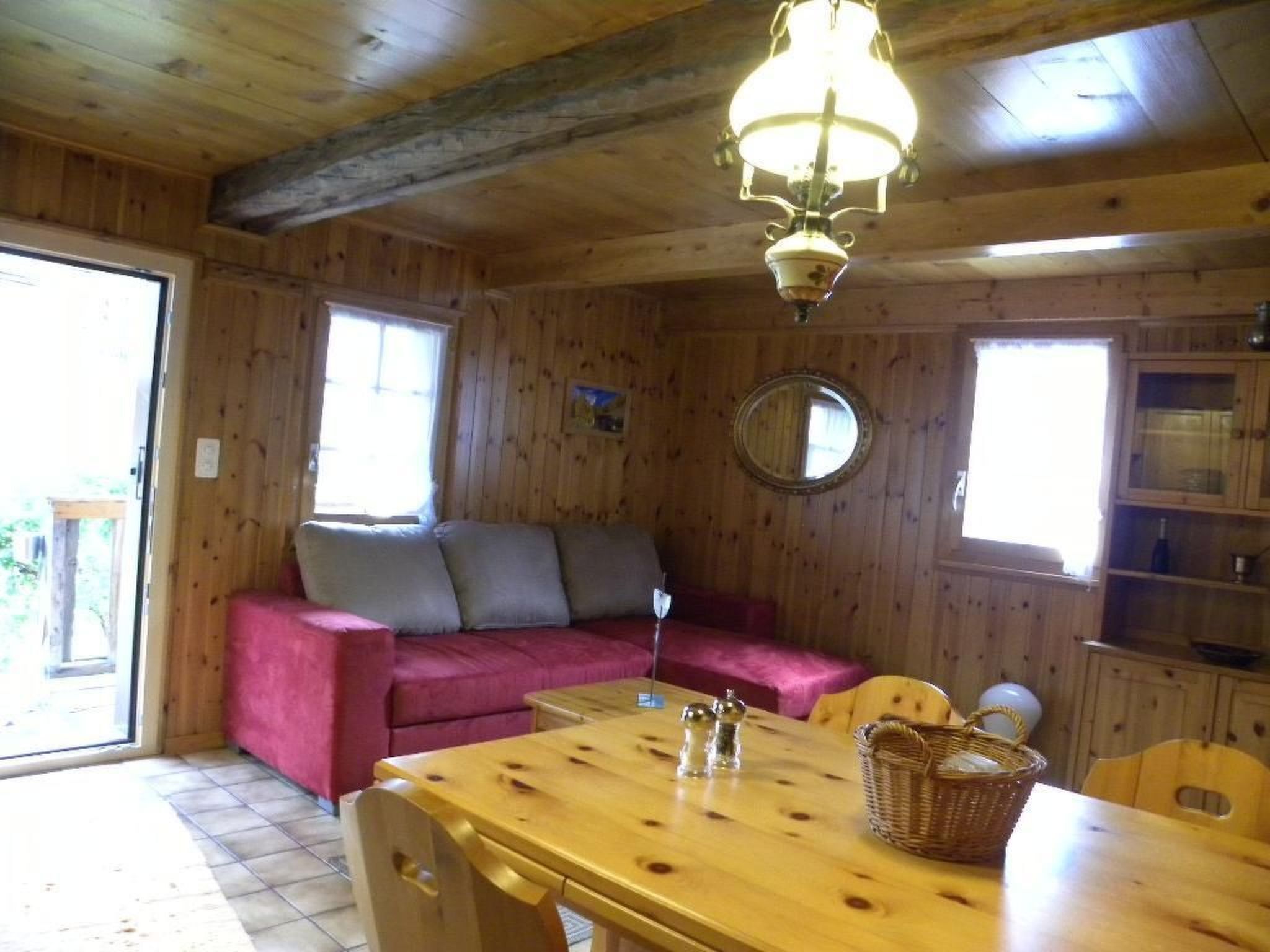 Ein Holzblockhaus-Interieur mit Esstisch, Sofa und einer Kronleuchter.