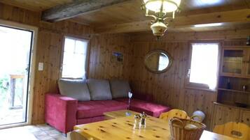 Ein Holzblockhaus-Interieur mit Esstisch, Sofa und einer Kronleuchter.