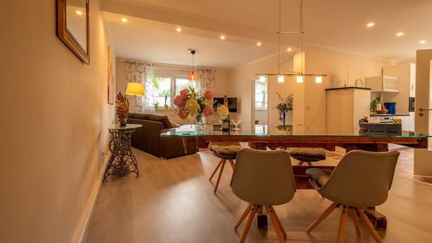 Un salon moderne avec une table à manger en verre, deux chaises, un canapé et une table basse.