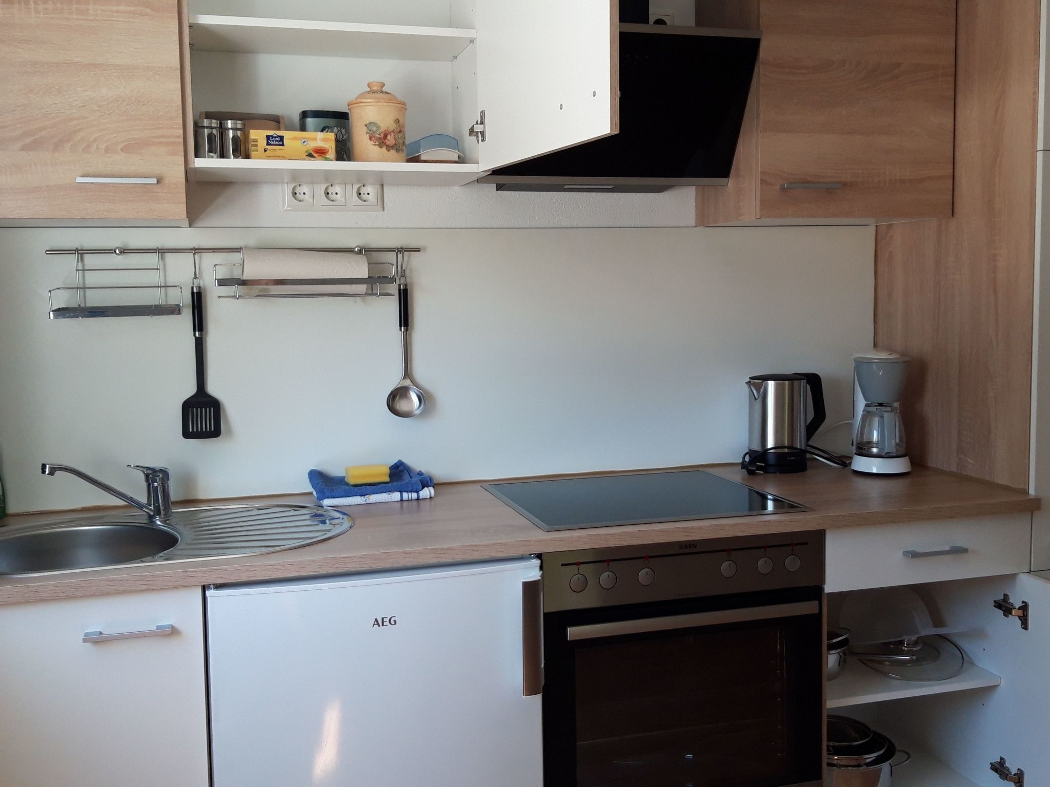 Une cuisine compacte équipée d’un four encastré, d’une machine à café et d’un évier.