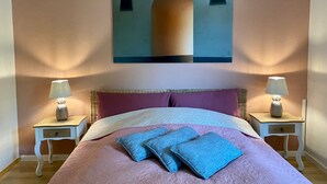 Een slaapkamer met een bed, twee nachtkastjes, een aan de muur hangend schilderij en twee lampen.