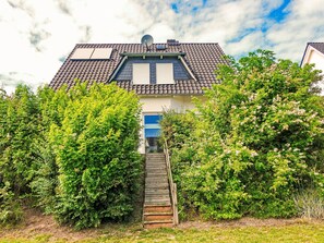 A house with a tiled roof, a satellite dish, and a wooden staircase leading to a blue door. - Vacation home  by Interhome (Bansin)
