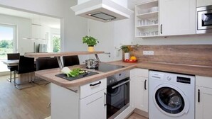 Eine moderne Küche mit Kochinsel, eingebautem Backofen und Geschirrspüler.