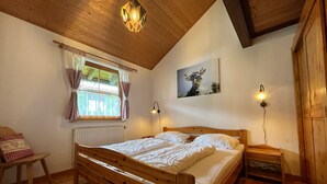 Un lit en bois dans une pièce avec une fenêtre, un radiateur et un tableau au mur.