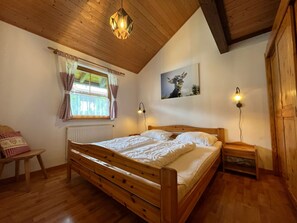 Ein Holzbett in einem Zimmer mit Fenster, Heizkörper und einem Bild an der Wand.