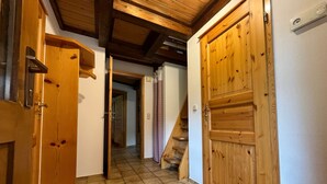 Un couloir avec des portes en bois, un sol carrelé et un escalier menant à une autre pièce.
