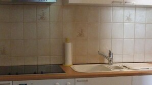 Eine Küche mit weißen Schränken, einer Edelstahl-Dunstabzugshaube, einem Spülbecken und einem Backofen.
