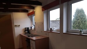 Eine kleine Küche mit Spüle, einer Kaffeemaschine und einem Fenster mit Blick auf Bäume.