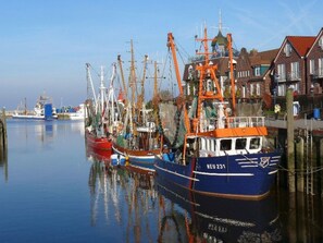 A harbor with several fishing boats docked, a clear sky, and buildings along the waterfront. - Logeerkamers "Gästezimmer Dellarte" by Interhome (Grossheide)
