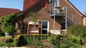 Ett hus byggt av tegel med ett rött tak, en satellitparabol och en liten balkong med en stol.
