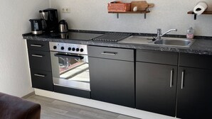 Ett modernt kök med svarta skåp, en diskho i rostfritt stål och en inbyggd ugn.