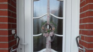 A white door with a glass panel and a floral wreath. - Friedel by Interhome (Grossheide)