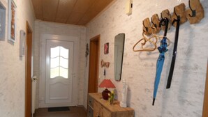 A hallway with a wooden door, a mirror, and a coat rack with hats and a blue umbrella. - Friedel by Interhome (Grossheide)