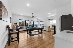 A spacious living area with a pool table, ceiling fans, and a large window offering a view of the outdoors. - Private Hot Tub Condo with Panoramic Lake View, Free Tickets, Game & Fitness Rooms,Cmty Amenities (Kimberling City)