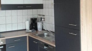 Eine moderne Küche mit dunklen Schränken, einem Geschirrspüler und einer Kaffeemaschine.