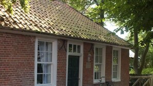 Ein Gebäude aus roten Ziegeln mit einem geziegelten Dach, weißen Fensterrahmen und einer Tür.