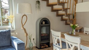 Ein gemütliches Wohnzimmer mit Kamin, einem blauen Sofa, einem Holzesstisch und weißen Stühlen.