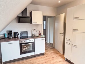 Eine kompakte Küche mit Backofen, Kaffeemaschine und Spüle.