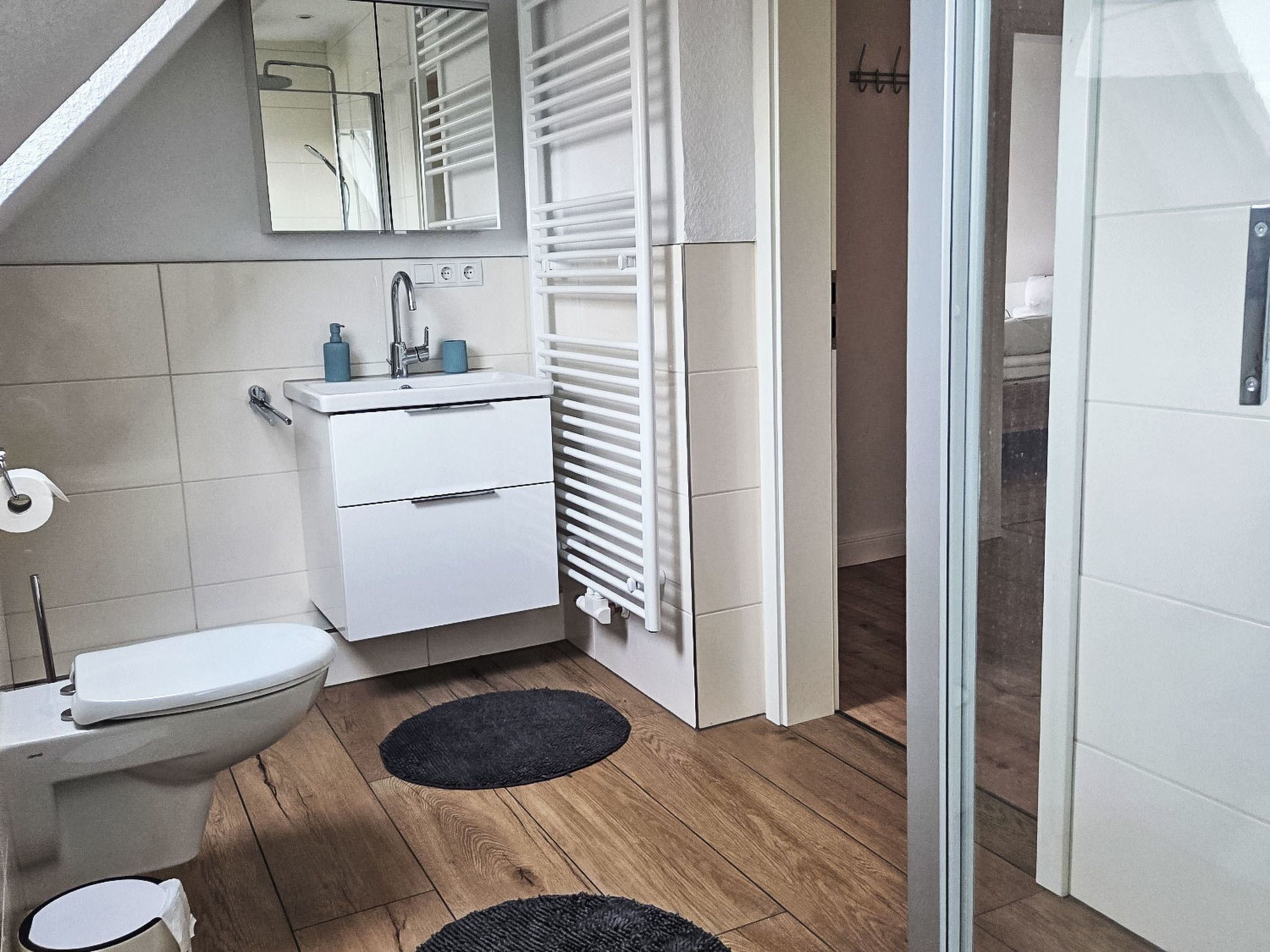 A modern bathroom with a toilet, sink, and mirror.