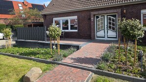 A residential house with a brick facade, a tiled roof, and a front entrance with double doors. - Sonnenschein EG by Interhome (Nessmersiel)
