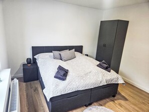 A bedroom with a bed, a wardrobe, a nightstand, and a heater. - Sonnenschein EG by Interhome (Nessmersiel)