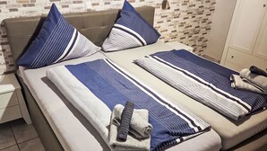 A bed with striped bedding, pillows, and towels. - Vacation home Max by Interhome (Nessmersiel)