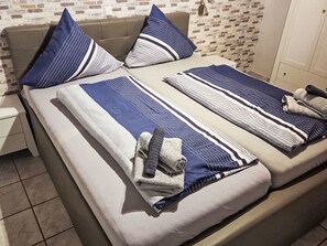 Ein Bett mit gestreifter Bettwäsche, Kissen und Handtüchern.