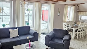 A living room with a sofa, armchair, coffee table, dining table, and chairs. - Vacation home Max by Interhome (Nessmersiel)