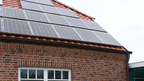 Un edificio de ladrillo con tejado de baldosas y paneles solares.