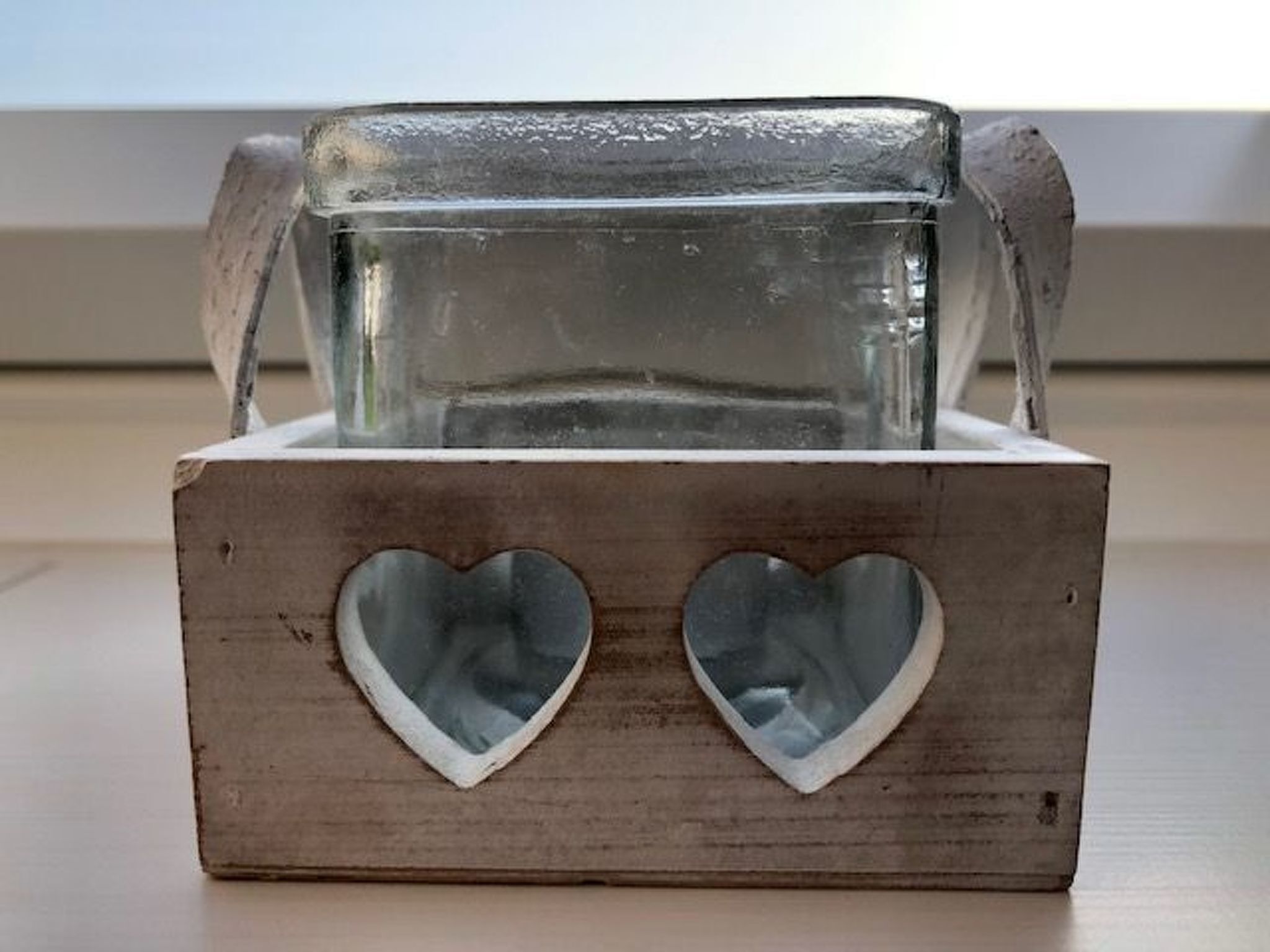 En trälåda med ett glasbehållare inuti, och hjärtformade utskärningar på framsidan.