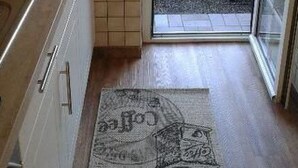 Eine Küche mit gefliestem Rücksprung, Holzboden und Teppich mit Zeichentrickfigur.