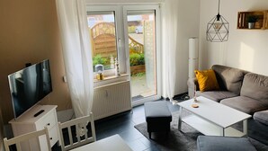 Ein modernes Wohnzimmer mit Flachbildfernseher, einer Couch, einem Couchtisch und einem Essbereich.