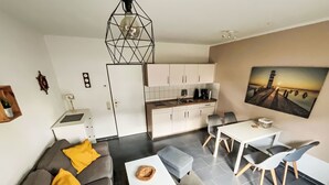 Eine moderne Wohnung mit Wohnbereich, Küchenzeile, Essbereich und einem Bild an der Wand.