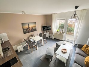 A modern living room with a dining area, a flat-screen TV, a painting, and a view of the outdoors. - Wohnung mit eigener Terrasse und Panoramablick by Interhome (Nessmersiel)