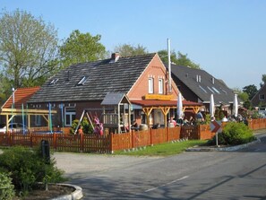 Ein traditionelles Gebäude im europäischen Stil mit roter Backsteinfassade, geneigtem Dach und Holzzaun.